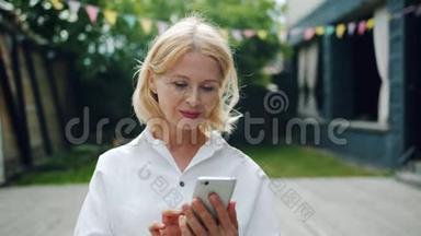 漂亮的成熟女人在户外使用智能手机触摸屏幕